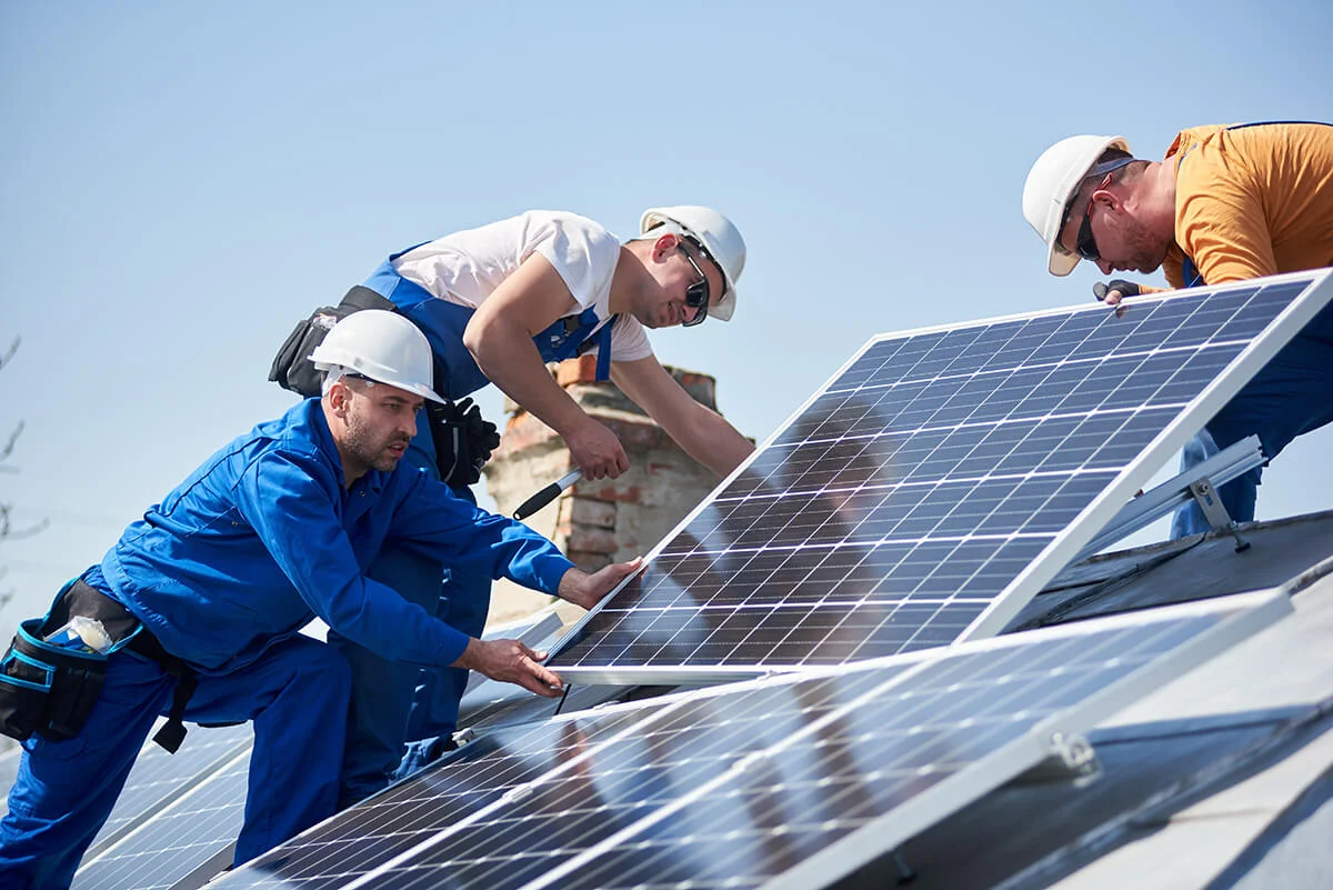 Techniciens posant des panneaux solaires sur le toit d’une maison
